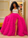 Woman wearing a white top and bright pink feathered skirt in an indoor setting.