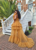 Woman in a yellow ruffled dress standing on a staircase with a brick building and palm tree in the background.