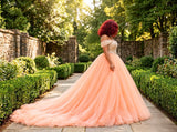 Side view of the St Zandas Aurelia gown showing draped off-shoulder sleeves, layered peach tulle and a sweeping train