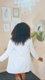 Person wearing a white couture coat in a room with decorative elements