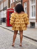 Woman wearing a yellow ruffled dress on a street with a red phone box in the background