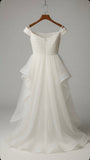 White wedding dress on a wooden hanger against a plain background