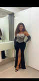 Woman in a black and white dress with a high slit standing in front of a mirror.